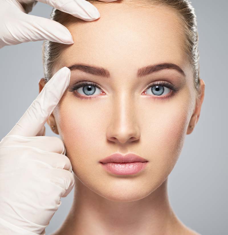 Schönheitschirurg ertastet Augenbraue von junger Frau